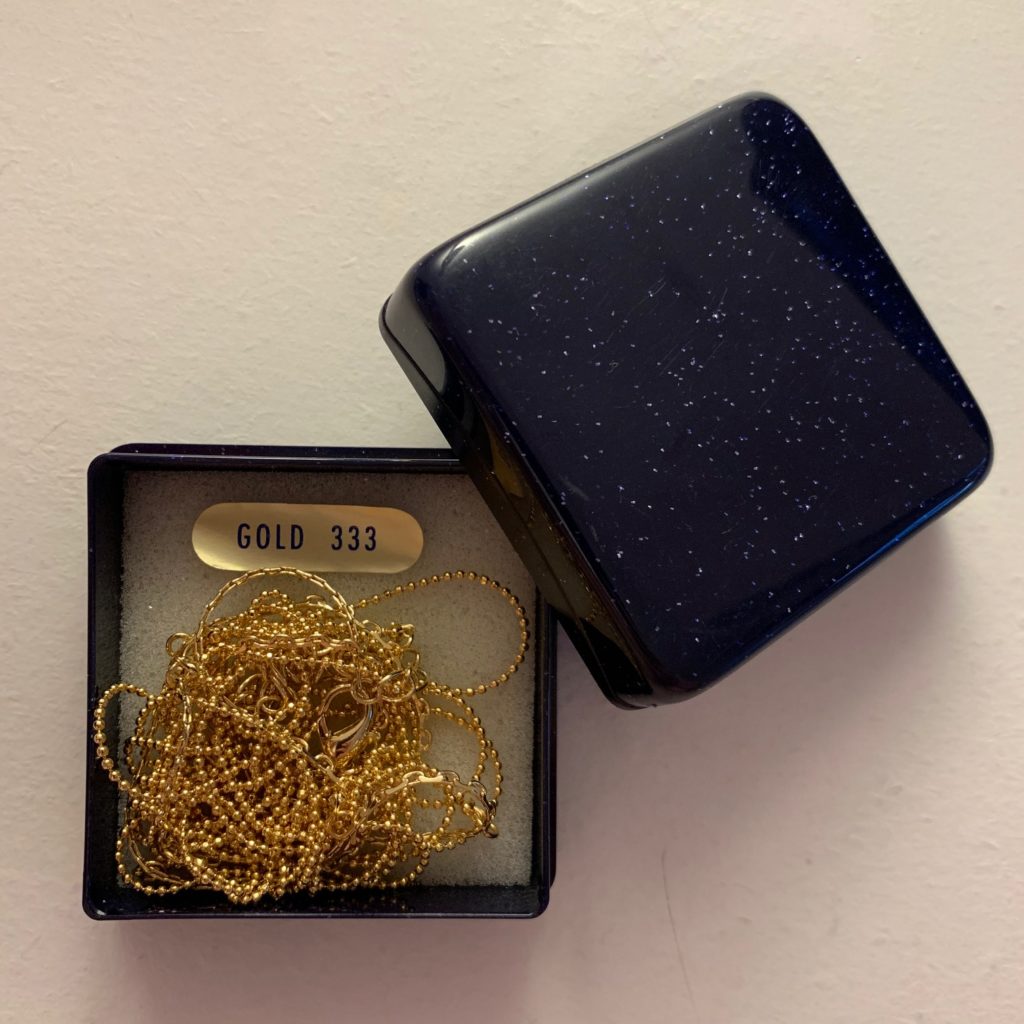Das Bild zeigt ein Schmuckschächtelchen mit einer Goldkette darin