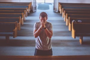 Das Bild zeigt einen betenden Mann in einer Kirche